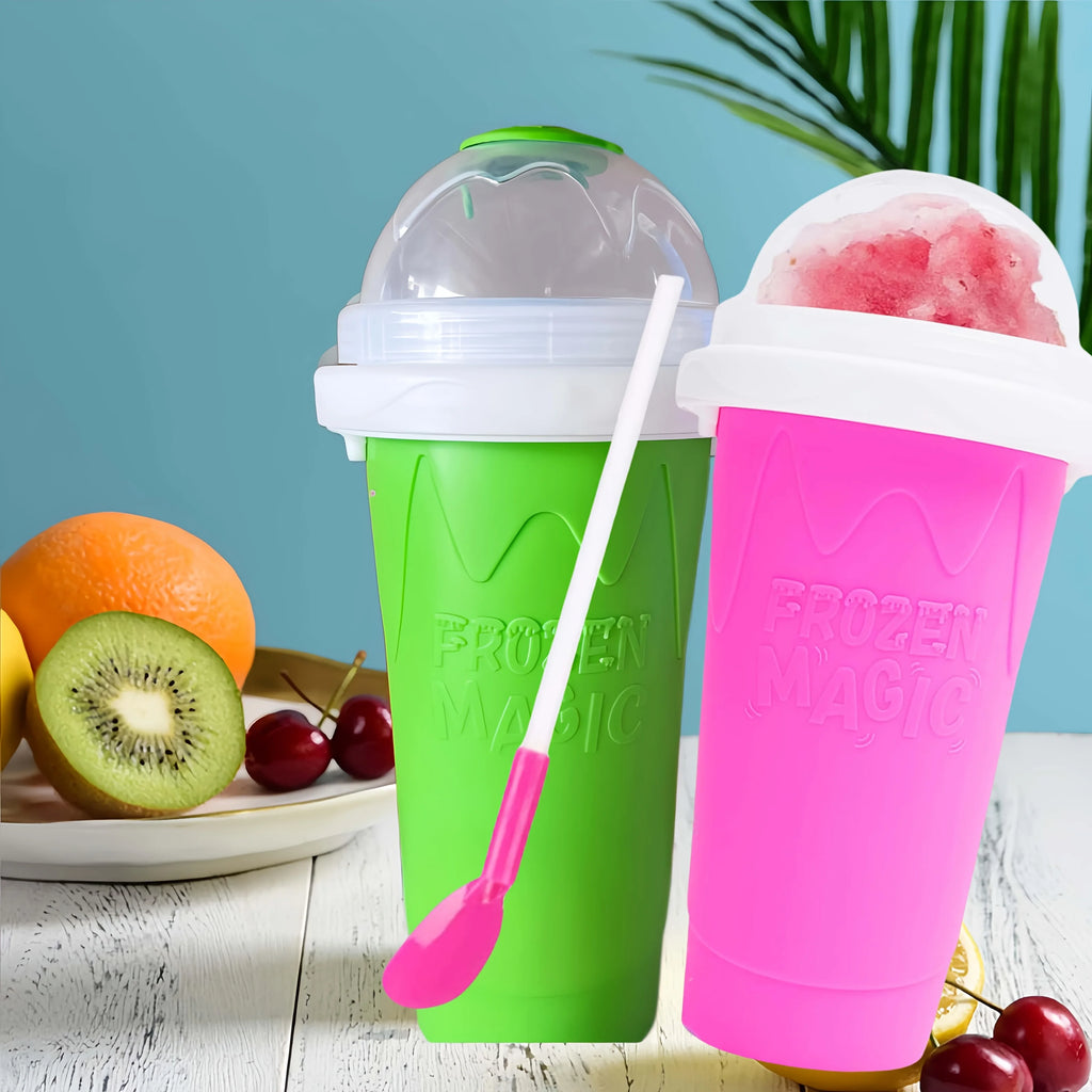 Bright green and pink silicone slushy maker cups with lids, straws and spoon attachments on a table with fruit.