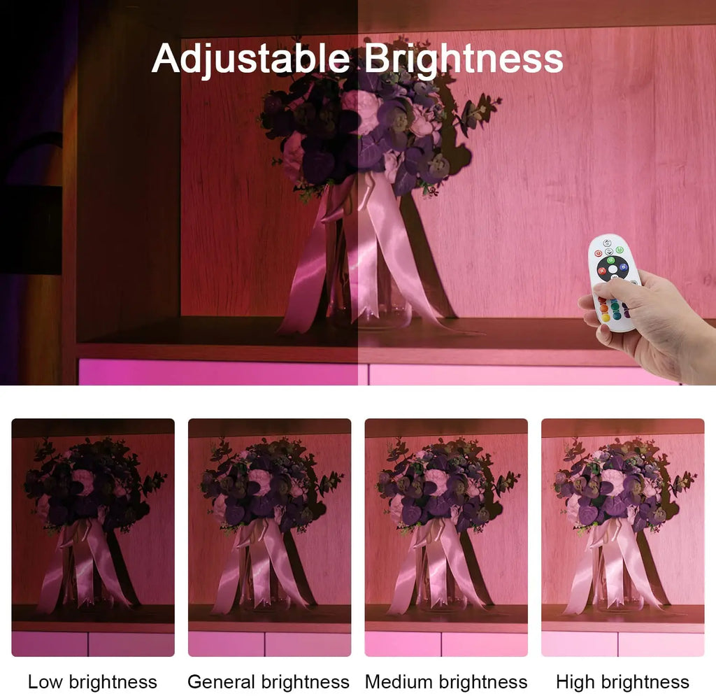 A hand using a remote to adjust the brightness and pink-toned sunset hue of an LED projection lamp on a floral display.