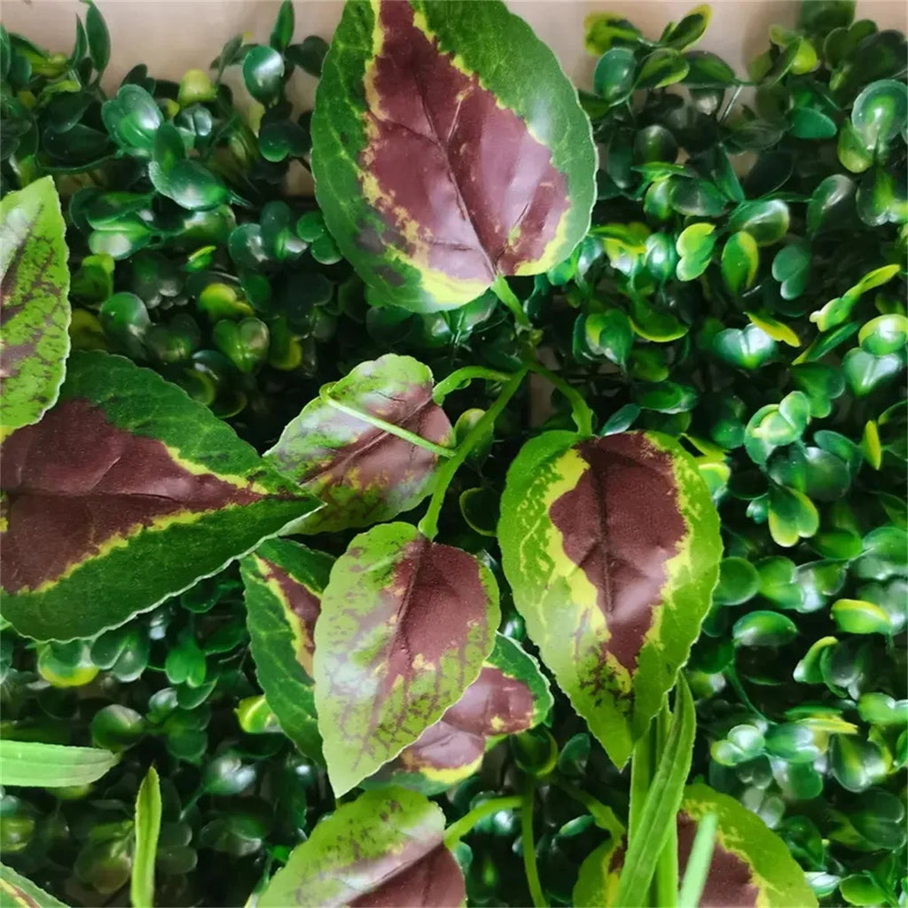 Artificial green wall panel featuring small, dense plastic leaves accented by larger, burgundy-and-green variegated leaves.