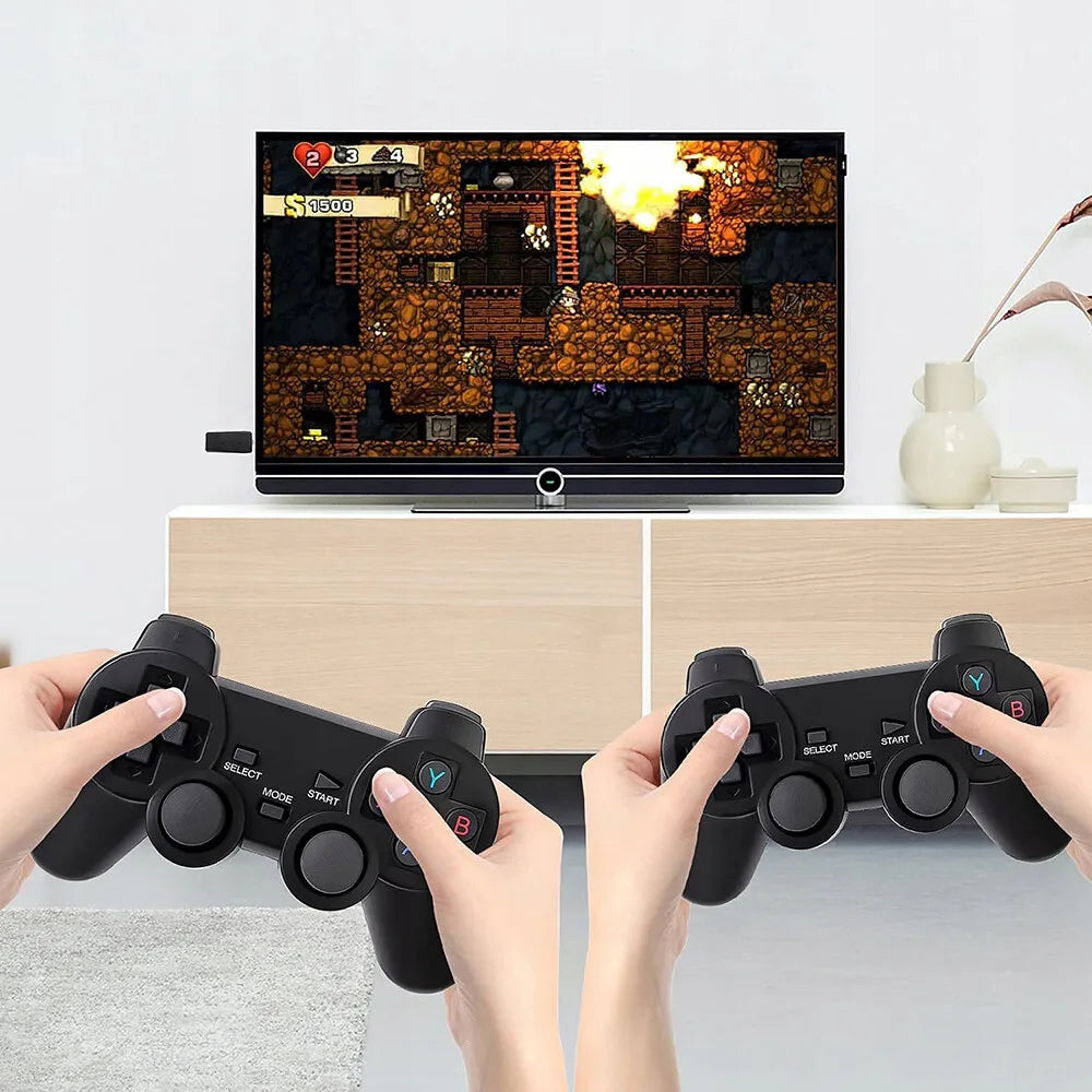 Two black wireless game controllers held in hands, with a retro game playing on the TV screen behind them.