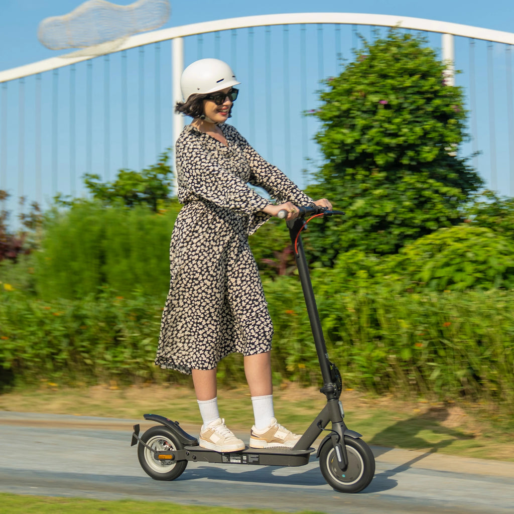 Woman riding a black 5TH WHEEL V30Pro electric scooter on a paved path outdoors.