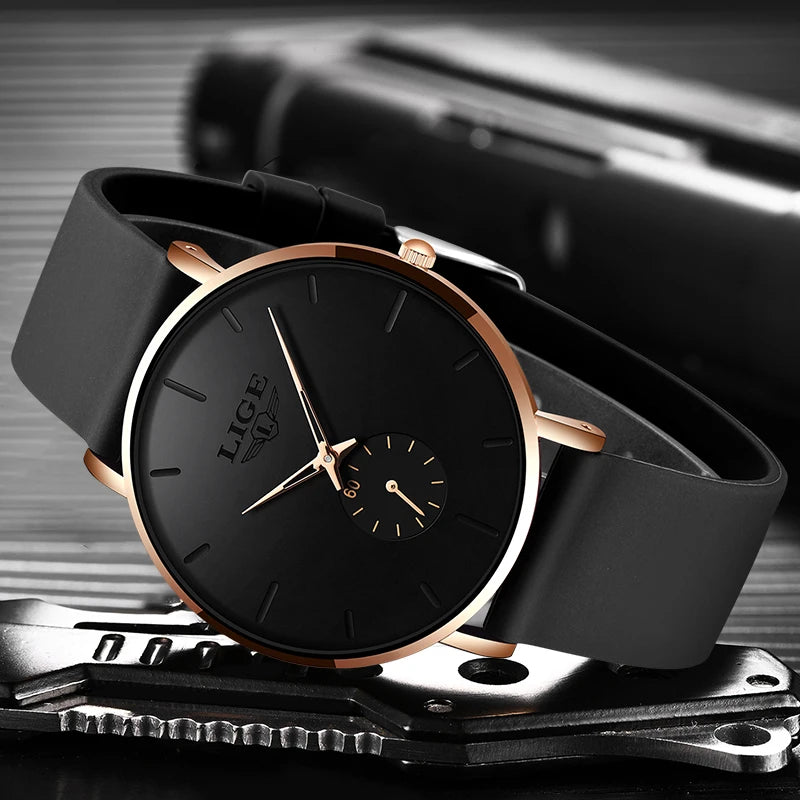 Ultra-thin black quartz watch with round gold bezel, black silicone strap, and minimalist dial with sub-second hand.