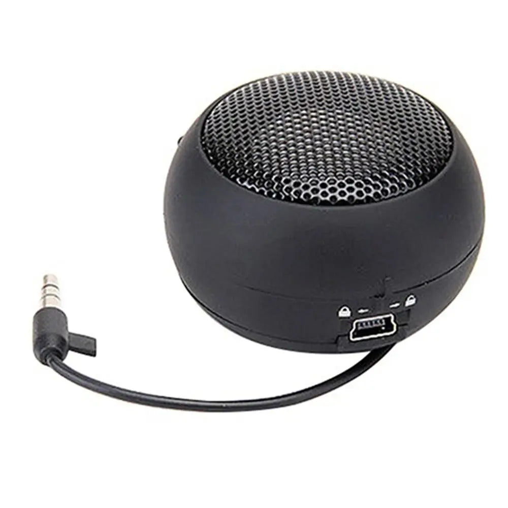 Small, round, black portable speaker with a metal mesh grille and integrated 3.5mm jack cable.