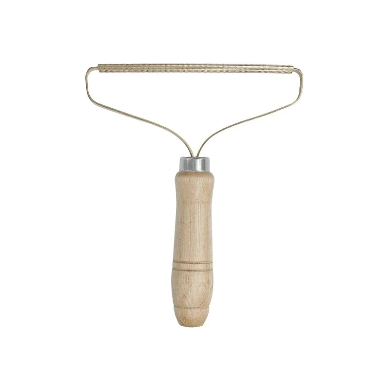 Fabric shaver with a ribbed metal edge and a light wooden handle, isolated on a white background.