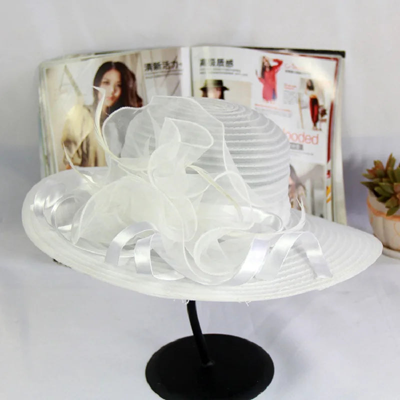 Elegant white wide-brim occasion hat featuring delicate sheer ruffles and ribbon detailing.