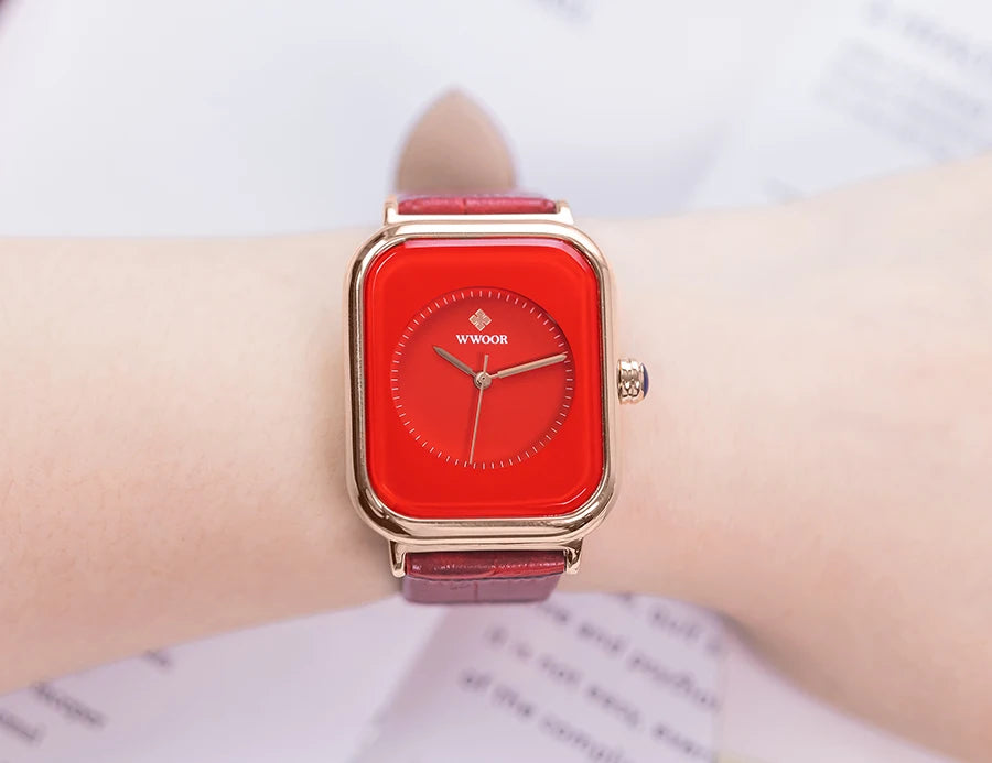 Ladies' watch with a square red dial, gold-tone case and a matching red leather strap worn on the wrist.