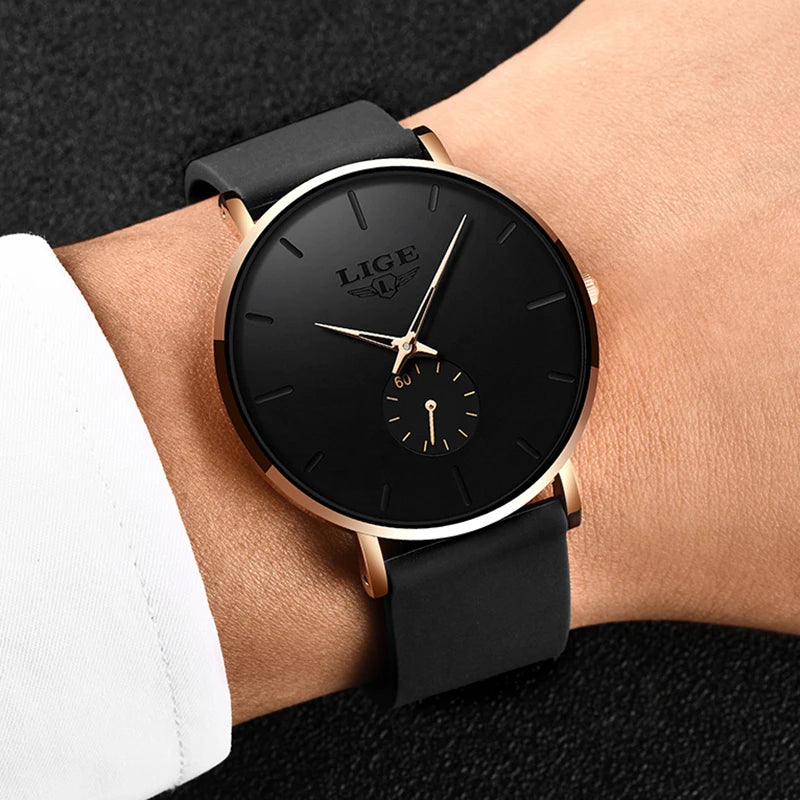 Men's quartz watch with round black dial, rose gold case, and black silicone strap on a wrist.