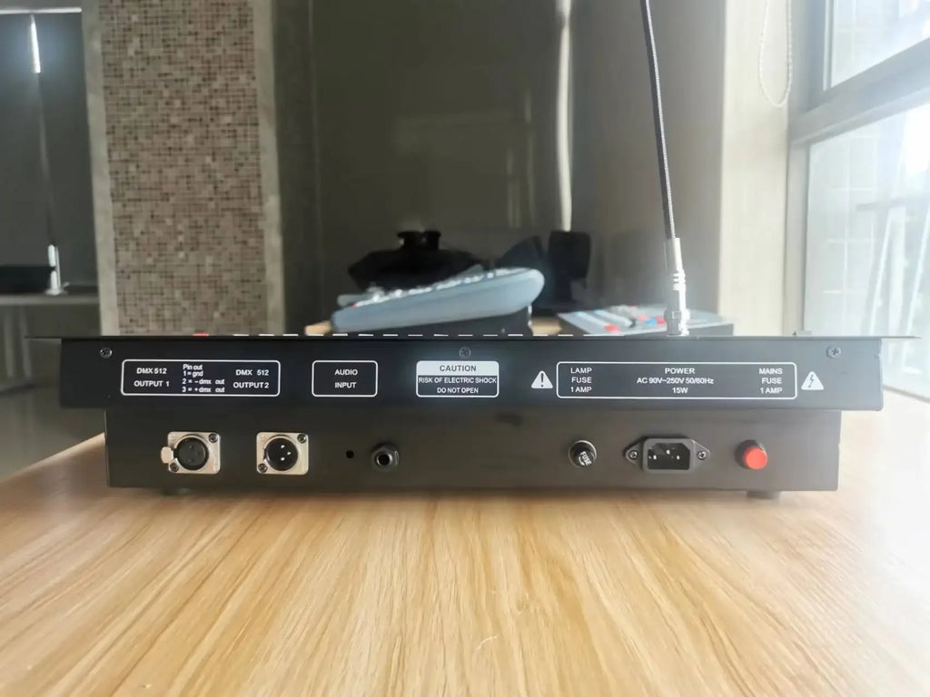 Rear view of a black 512 DMX stage lighting controller featuring dual XLR outputs, audio input, and power socket.