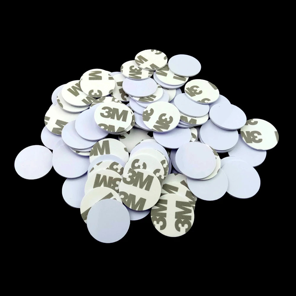 Pile of white circular adhesive foam pads with 3M brand markings on the peel-off backing.