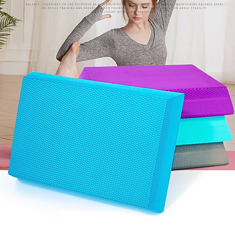 A stack of textured blue, purple, teal, and grey TPE foam balance pads for stability and exercise training.