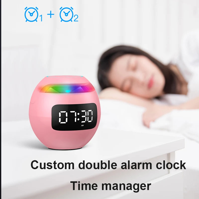 A compact, pink sphere-shaped Bluetooth speaker and LED alarm clock with dual alarm settings and colourful top light.