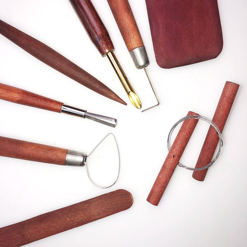 A set of wooden-handled pottery and clay sculpting tools, including wire loops, metal blades, and a smoothing rib.