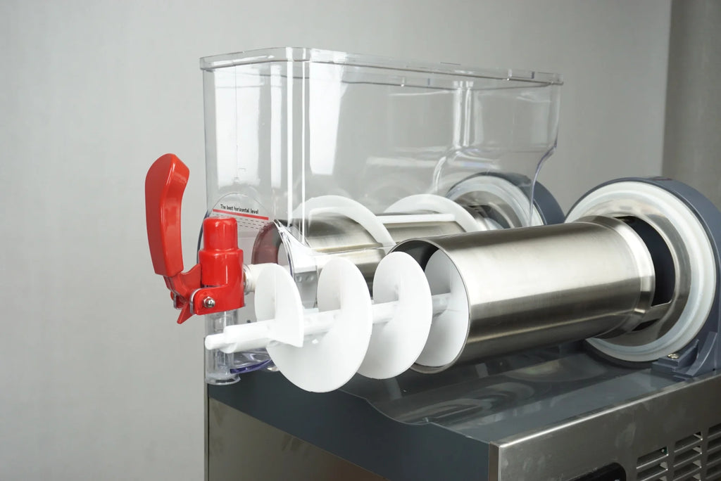 Close-up of a commercial slush machine with a clear bowl, stainless steel cylinder, white auger, and red tap handle.