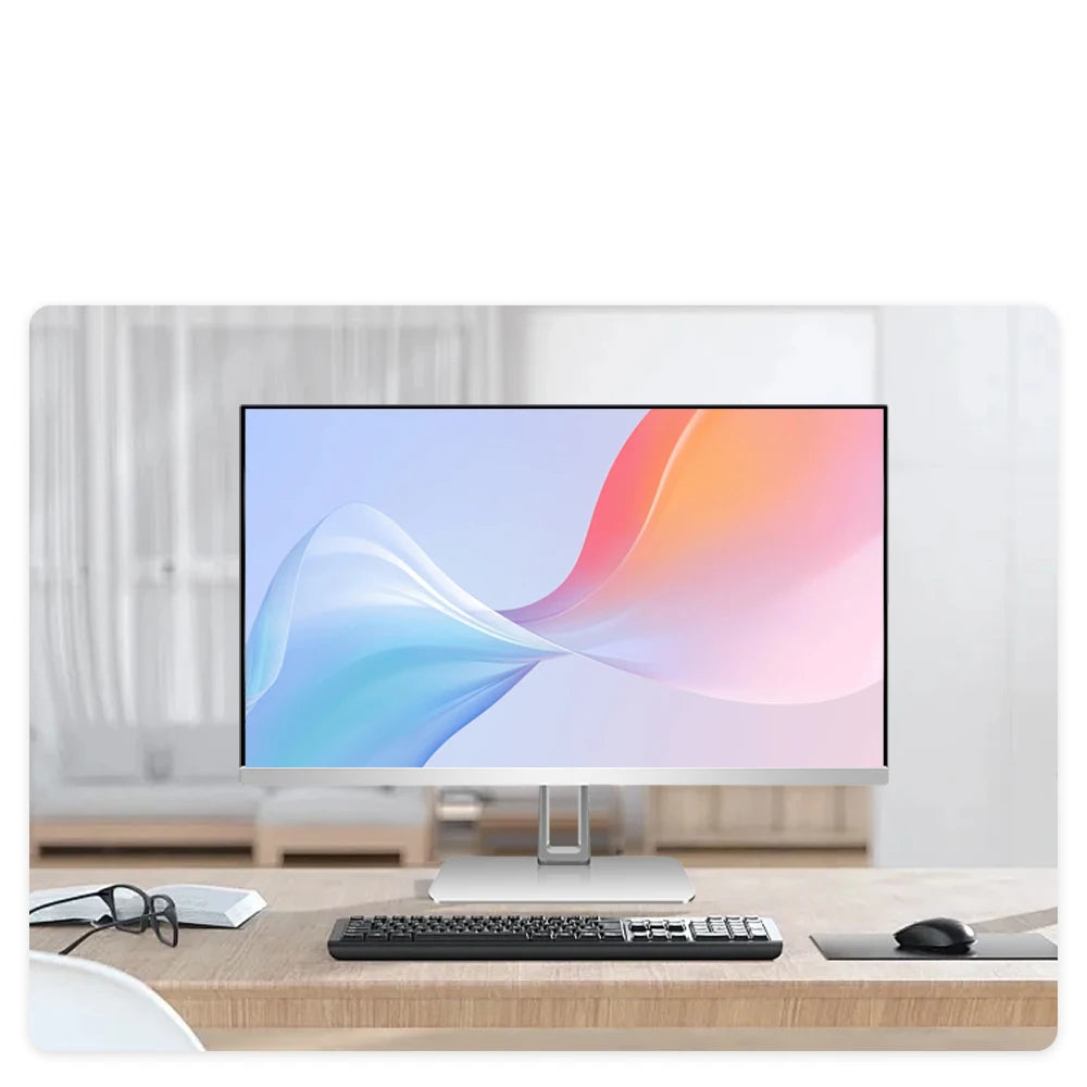 Sleek silver all-in-one desktop computer with a slim bezel display on a wooden desk, including keyboard and mouse.