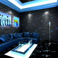 Modern black 3D geometric wallpaper with reflective blue accents, shown in a contemporary living room setting.