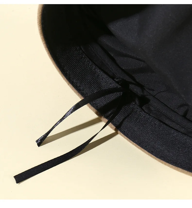 Close-up of a tan beret’s interior, featuring a black lining and a small, adjustable black ribbon tie.
