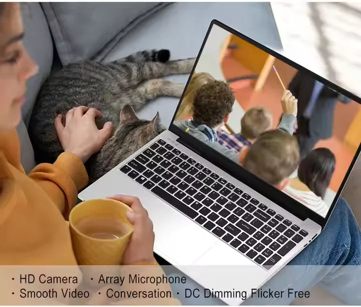 Silver 15.6-inch laptop with a black keyboard, shown displaying a video call, used by a person relaxing with a cat.