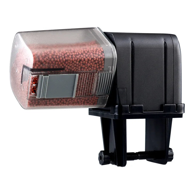 Black automatic fish food dispenser with a clear container filled with brown pellets and a mounting clamp.