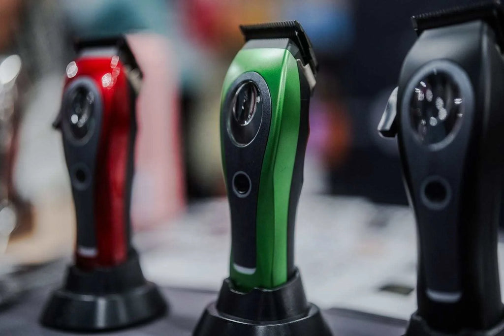 Three cordless hair clippers in red, green, and black standing in individual charging docks.