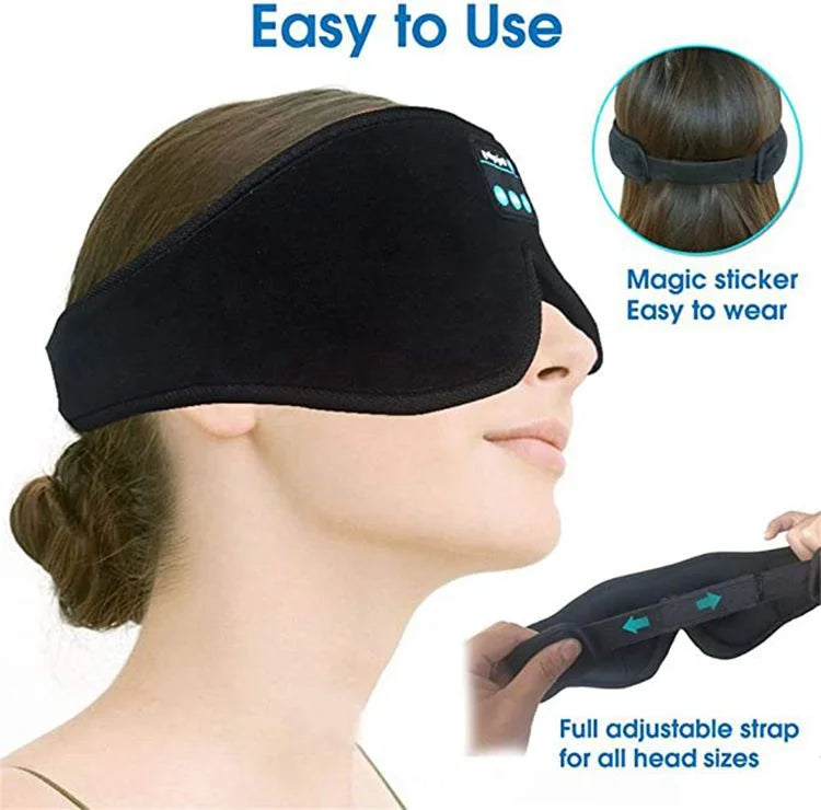 A person wearing a soft, black Bluetooth sleep eye mask with an adjustable hook-and-loop strap for a secure fit.