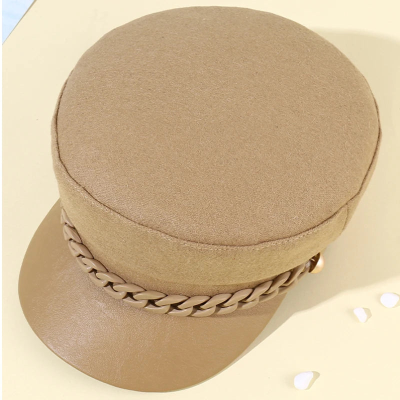 Tan felt baker boy hat with a faux leather peak and matching decorative chain trim.