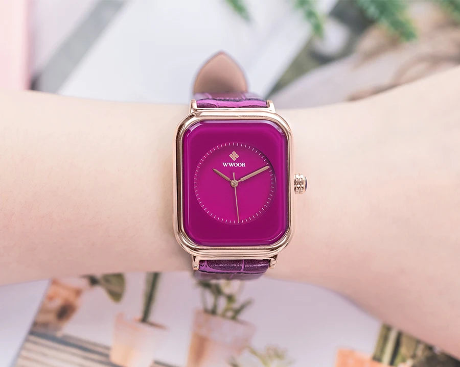 Ladies' square watch with a vibrant magenta face, rose gold case, and a textured purple leather strap on a wrist.