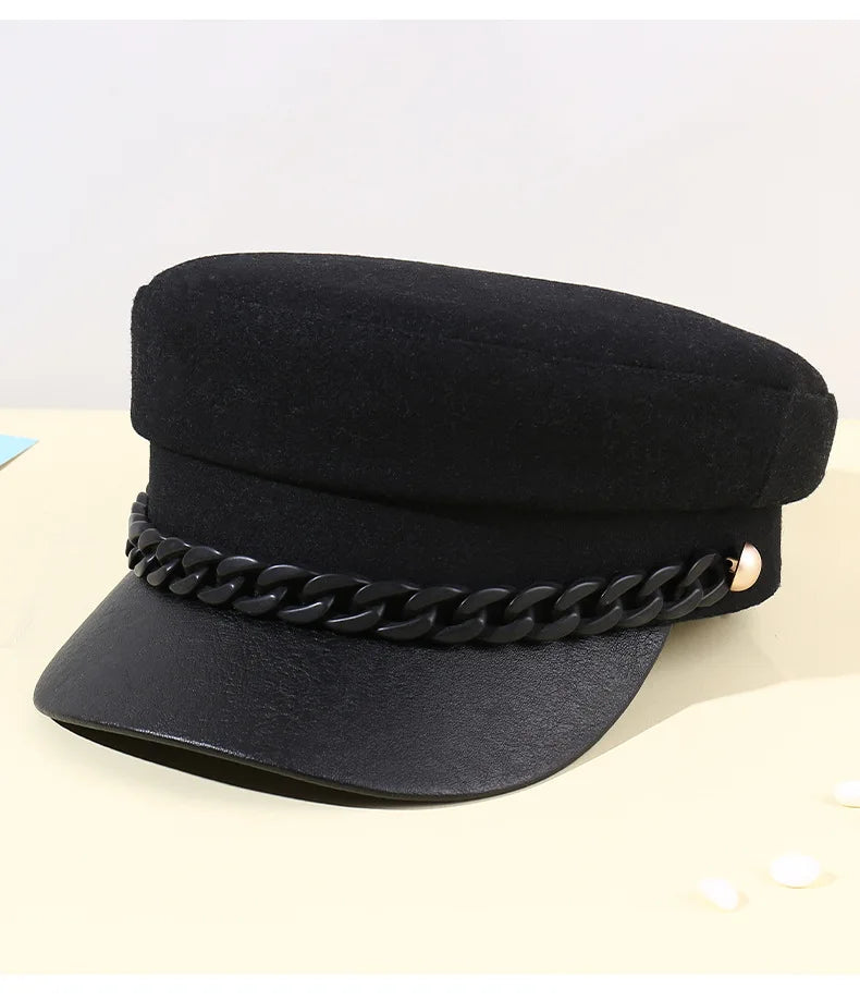 Black felt baker boy hat with a faux leather peak and a decorative black chain trim with gold-tone side studs.