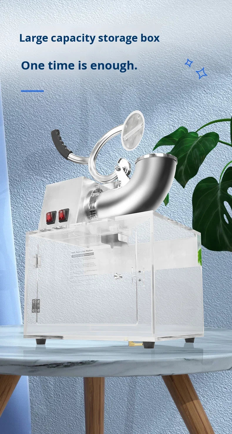 Electric ice shaver with stainless steel feed chute and a transparent acrylic storage box base on a table.