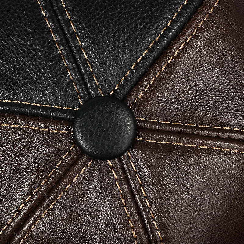 Close-up of a genuine leather baseball cap featuring black and brown panels with detailed contrast stitching.