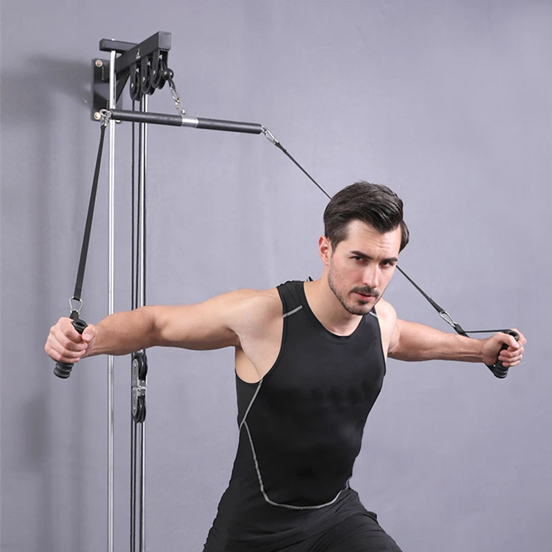 A man in a black tank top exercises using a wall-mounted cable pulley machine, holding handles in both hands.
