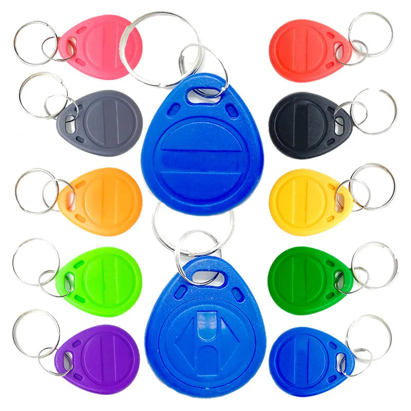 A set of multi-coloured plastic RFID key fob tags with metal key rings arranged on a white background.