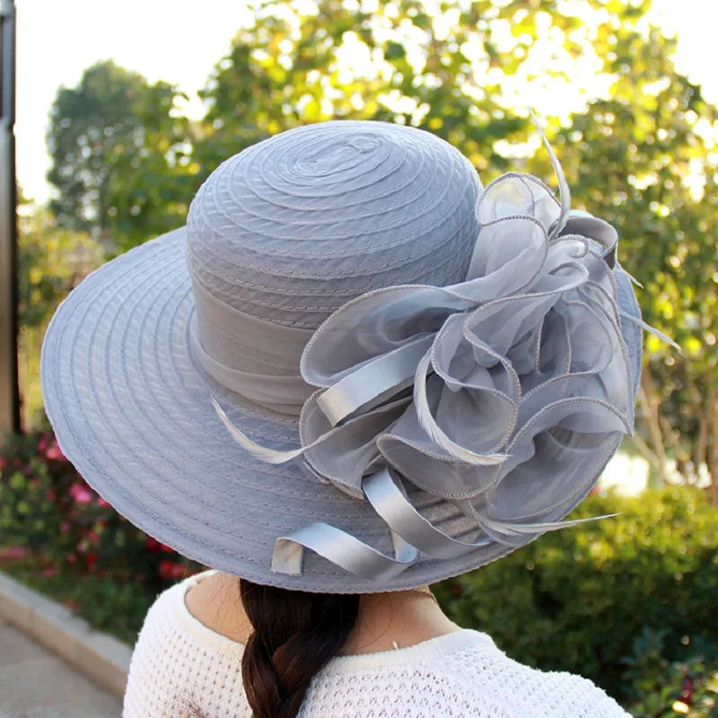 Grey wide-brim occasion hat featuring elegant organza floral detail and ribbon trim.