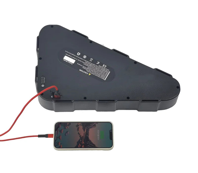 Black triangle e-bike lithium-ion battery pack with a red charging cable connected to a smartphone.