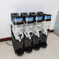Commercial 4-tank slush machine with clear containers, black base units, and individual dispensing handles.
