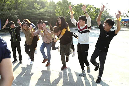 A group of young people having fun outdoors, dancing and piggybacking in a sunny park setting.