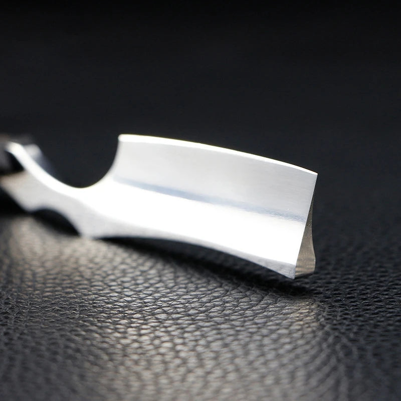 Close-up of a professional stainless steel straight-edge razor, featuring a sharp, polished blade on a black surface.