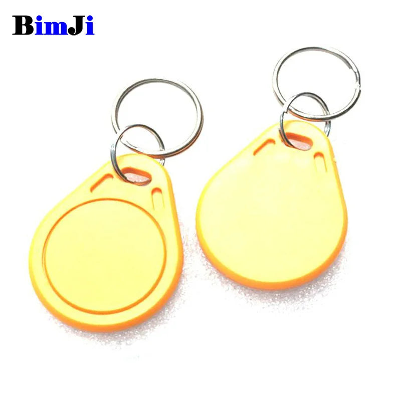 Two yellow plastic RFID key fob tags with metal key rings on a white background.