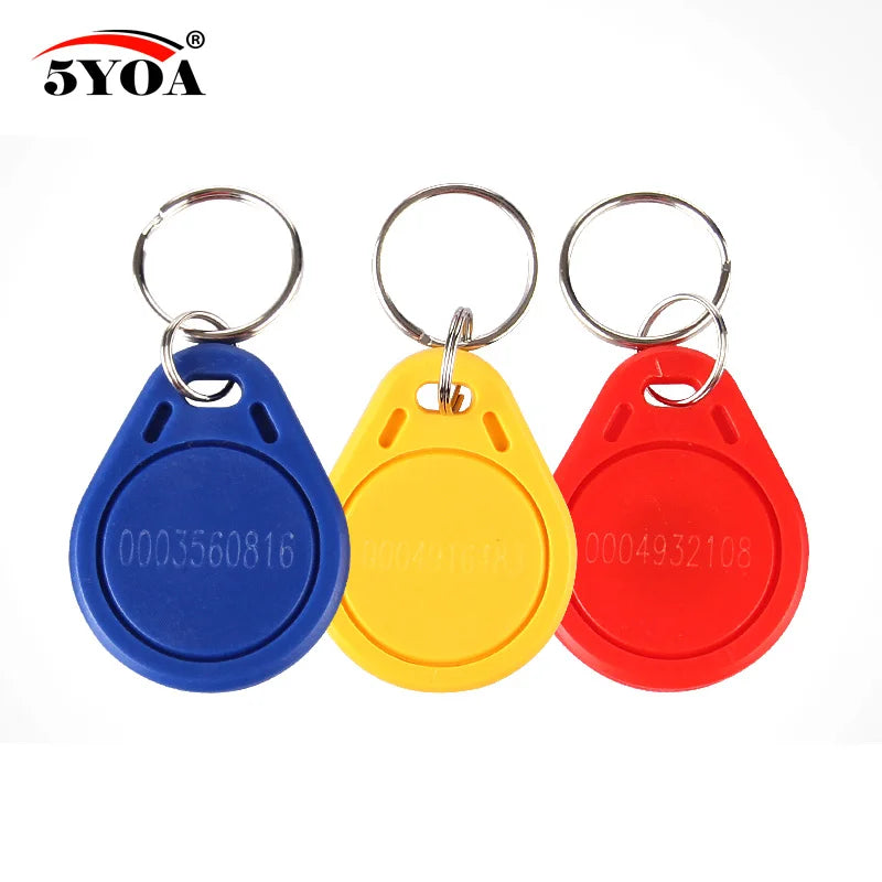 Blue, yellow, and red plastic RFID key fobs with metal keyring attachments and engraved identification numbers.