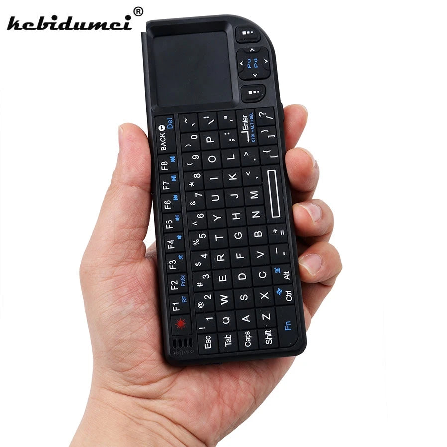Black plastic handheld mini wireless keyboard with QWERTY layout and integrated trackpad held in a person's hand.