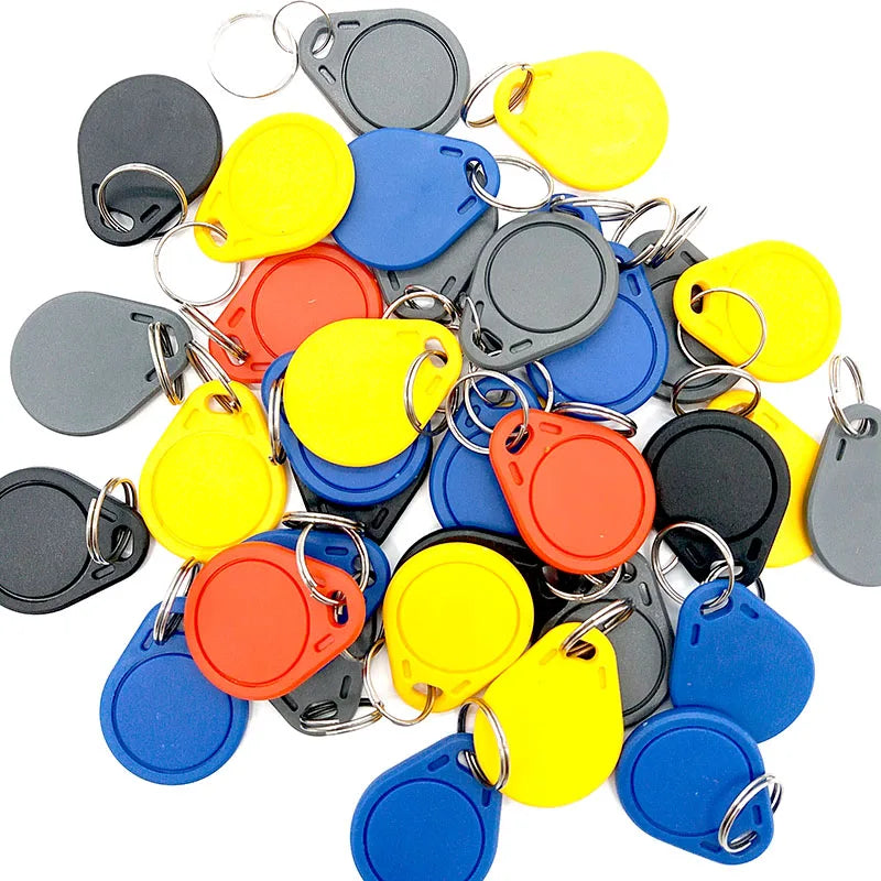 A pile of colorful plastic RFID key fob tags in red, yellow, blue, black, and grey, each with a metal key ring.