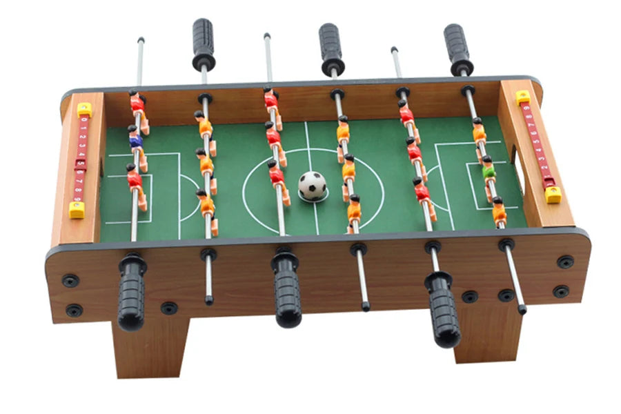 Tabletop foosball game with wood-effect finish, green pitch, ball, and score counters on a white background.