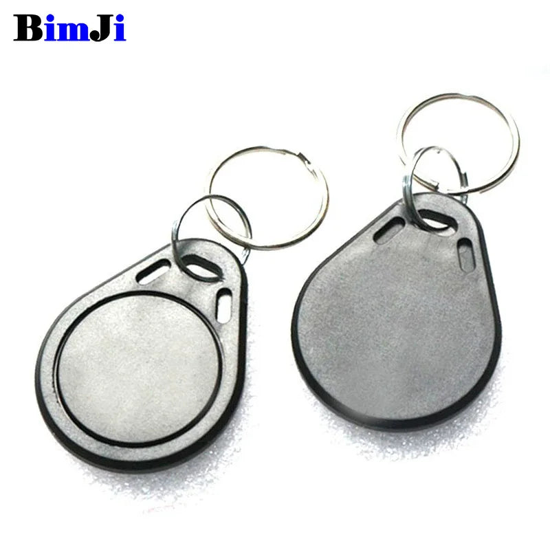 Two black plastic RFID key fob tags with silver metal key rings on a white background.