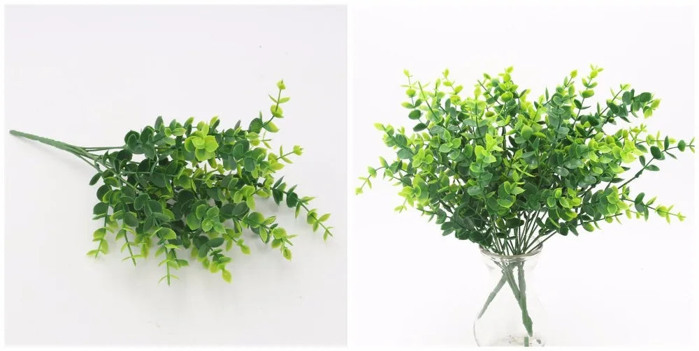 Artificial green plastic eucalyptus stems with small leaves, shown laid flat and arranged in a clear glass vase.
