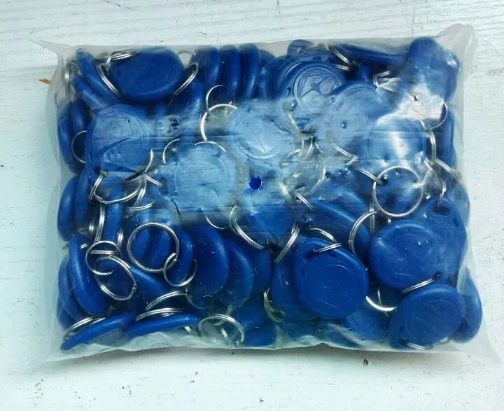 A plastic bag filled with many blue round RFID key fob tags, each attached to a metal split ring.