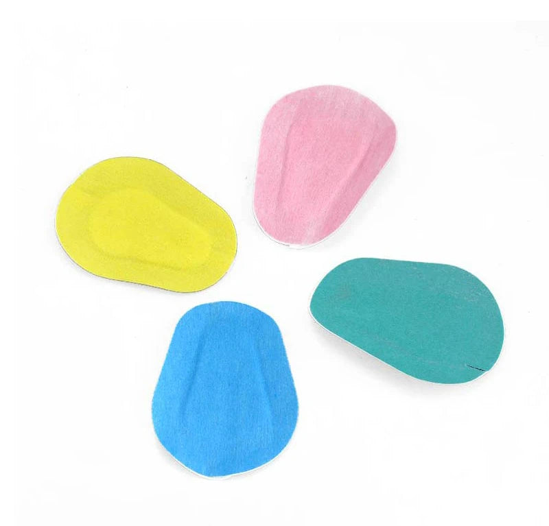 Four oval-shaped, non-woven fabric eye patches in pink, yellow, blue, and teal.