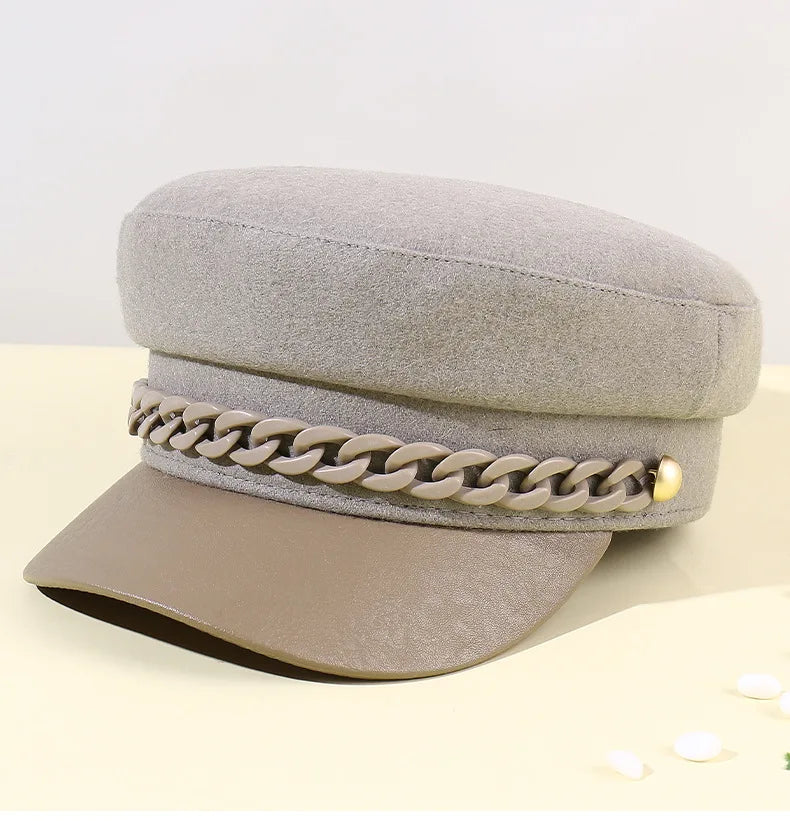Grey felt-effect baker boy hat featuring a decorative chain trim and a contrasting brown peak.