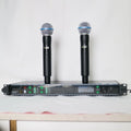 Dual wireless handheld microphone system featuring two black microphones and a digital receiver unit with LED displays.