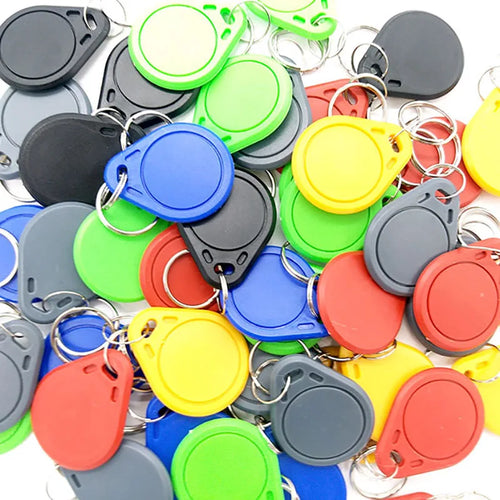 A pile of colorful plastic RFID key fob tags in red, blue, green, yellow, black, and grey with metal key rings.