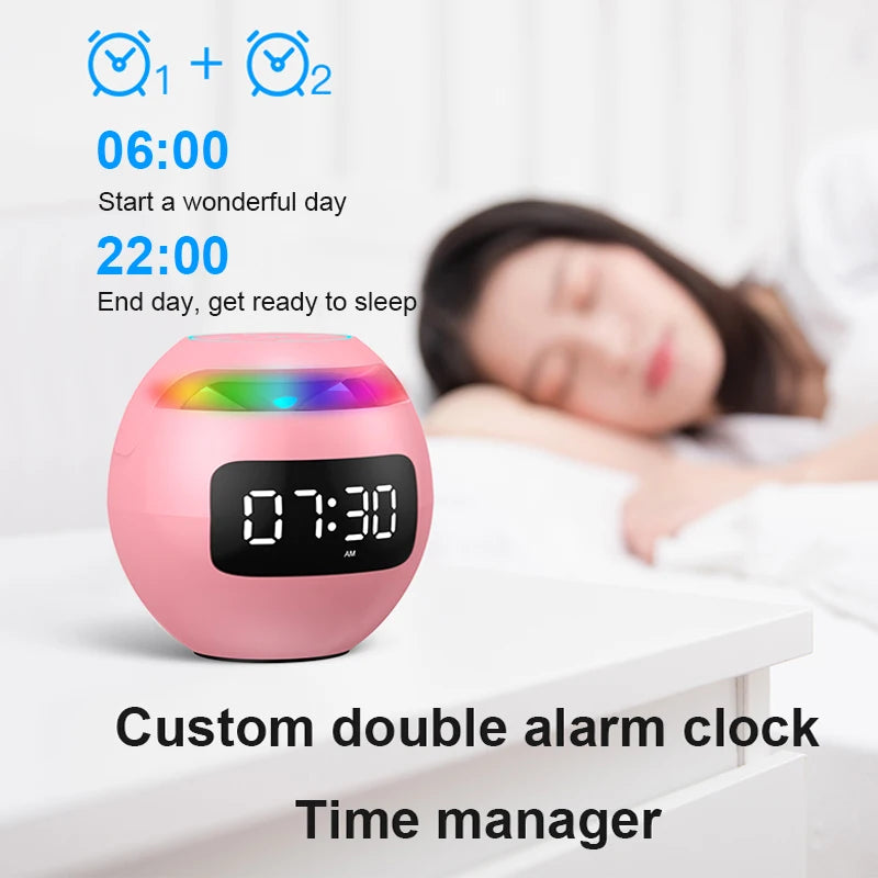 Pink spherical Bluetooth speaker and LED digital alarm clock with a colourful light bar, sitting on a bedside table.