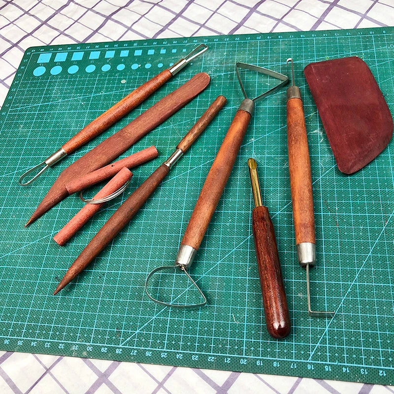 Set of wooden-handled pottery and clay sculpting tools including ribbon loops, carving knives, and a clay scraper.